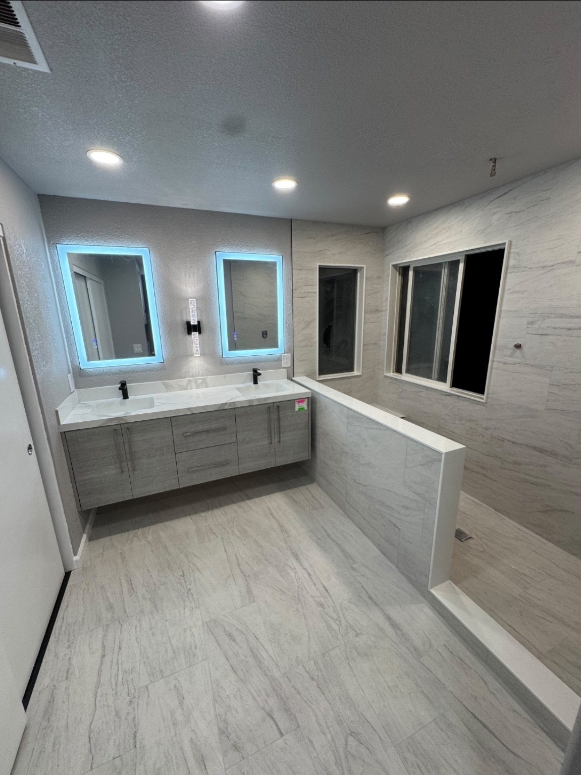 Finished bathroom remodel with double vanity and marble tile